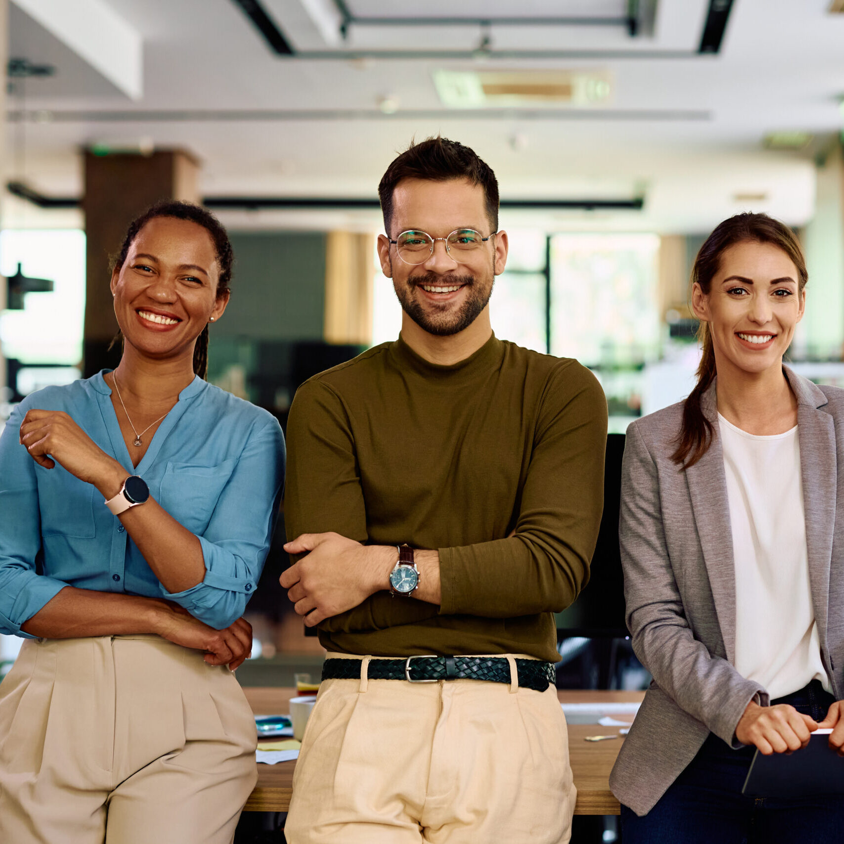 Happy business team in modern office looking at camera.